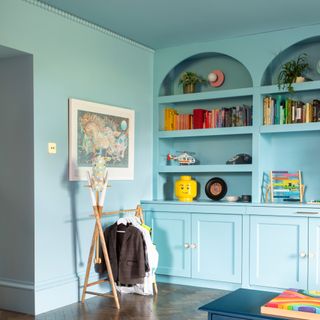 A sky blue-painted, colour-drenched room with arched, built-in bookcases