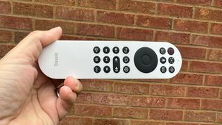 BenQ GV31 home cinema projector remote held in hand against brick wall