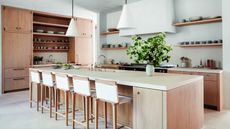kitchen with oak cabinetry and island, wood and rope bar stools, plaster walls and pendant