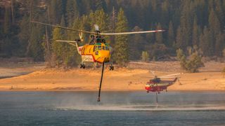 Two helicopters draw water from a drought effected reservoir