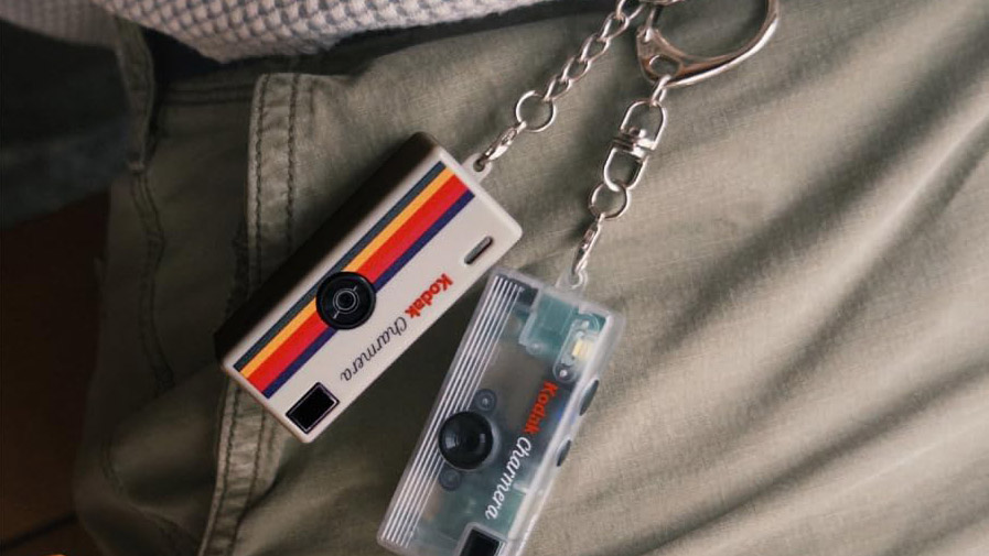 A lifestyle picture of two Kodak Charmera keyrings clipped on to a person's belt loop