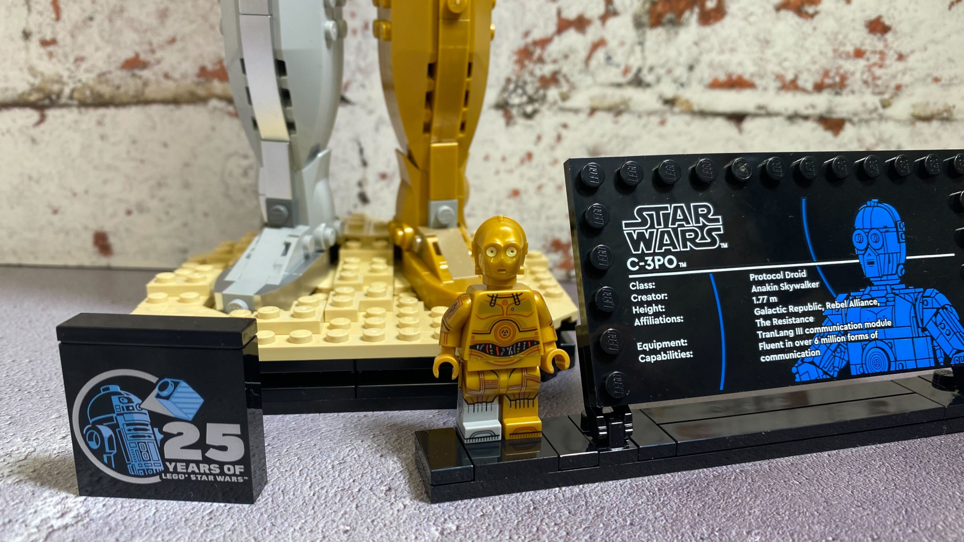 Minifigura de Lego C-3PO en una placa frente al modelo base