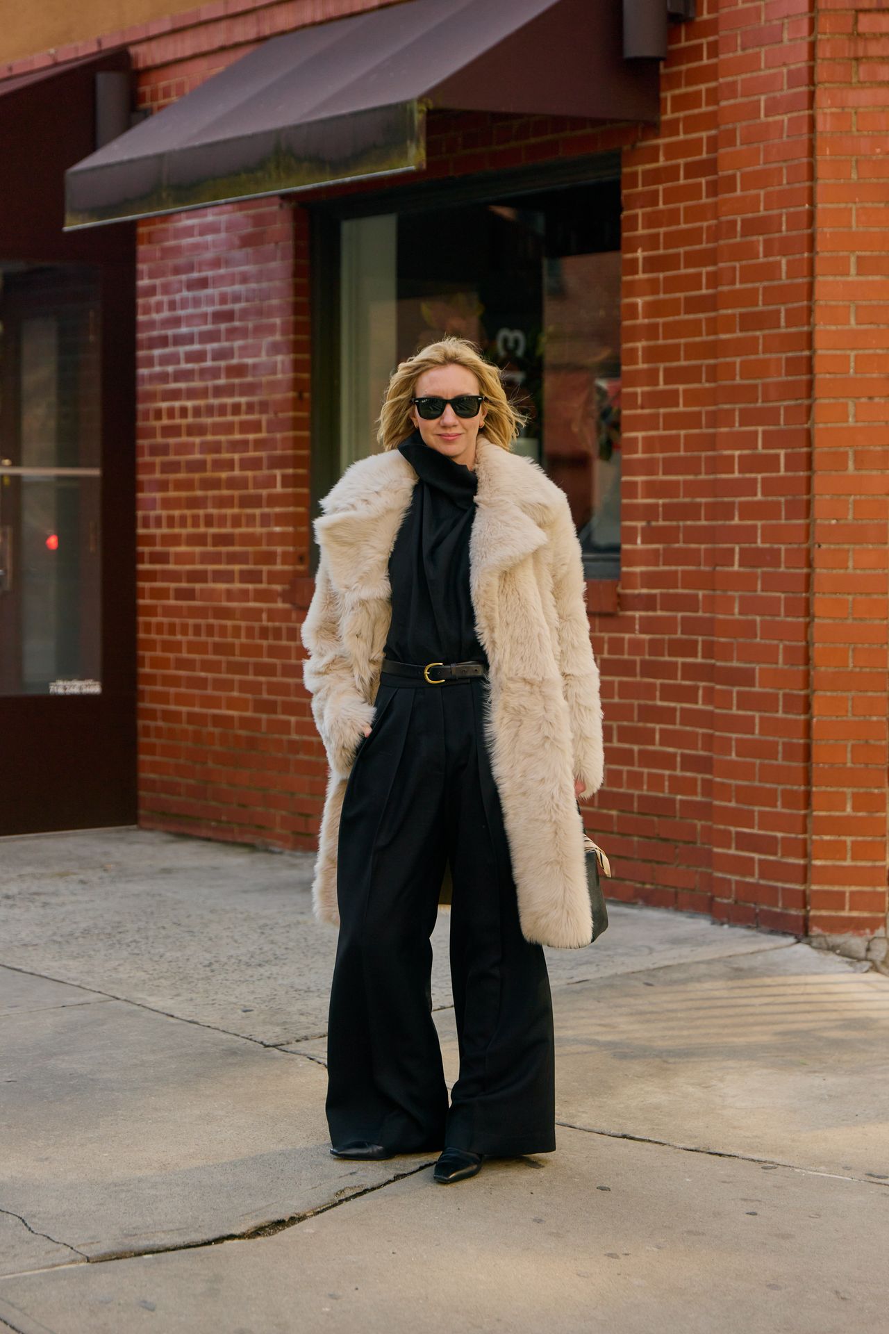 Lisa Aiken wearing a cream fur coat with a black sweater and black pants during F/W 25 fashion week in New York.