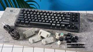 The Wooting 80HE in Ghost PCR case with black keycaps, on a stone surface with a blue background.