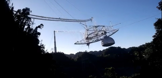A still image from video provided by the NSF shows the Arecibo radio telescope's massive platform falling to the ground.
