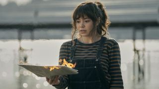 Auli'i Cravalho looking at a burning book in The Power