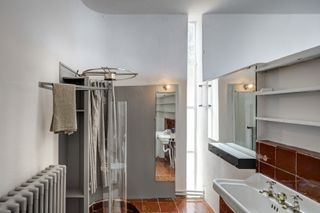 A white bathroom with a basin, a shower area and wall mirrors.