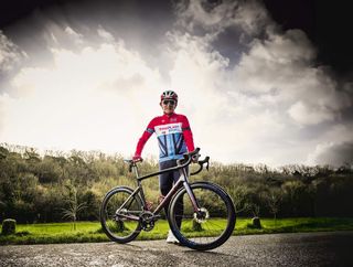 Nick Topley standing next to his bike in his cycling gear