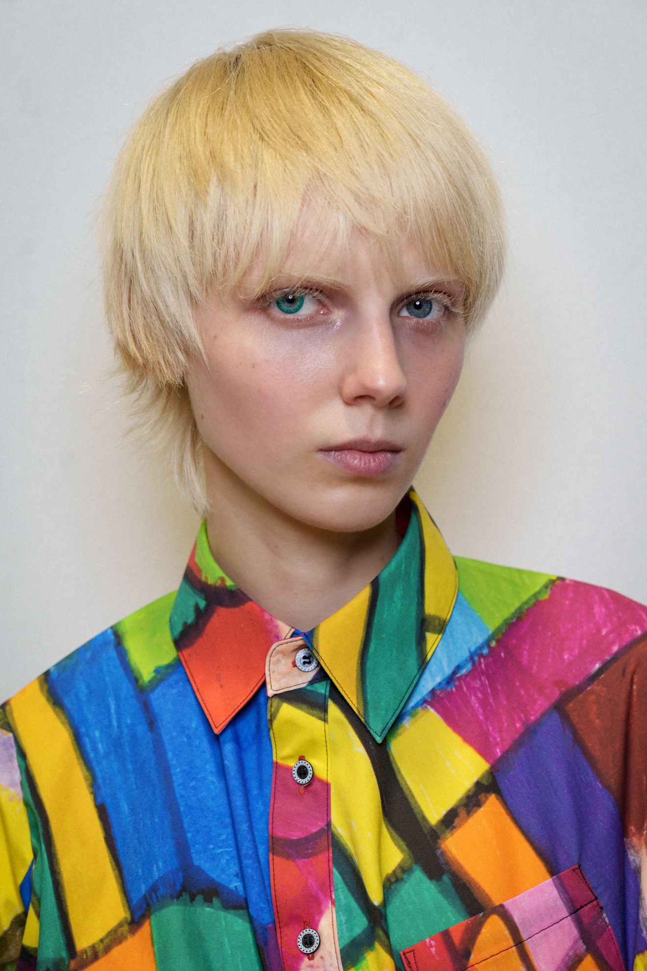 bleach blonde pixie cut with an eighties style colorful shirt