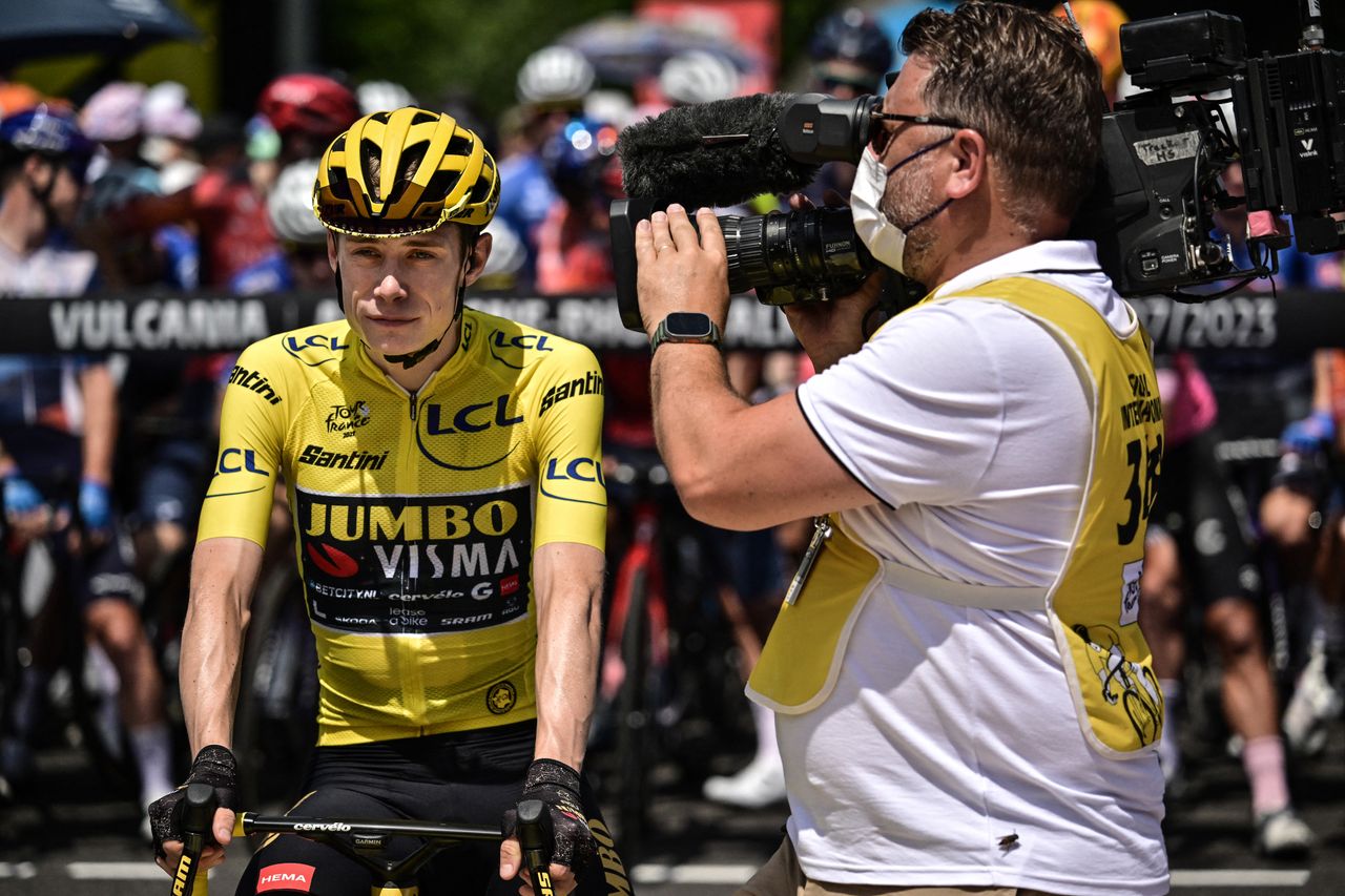 Jonas Vingegaard in the yellow jersey being filmed by a TV camera