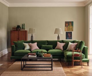 green corner velvet sofa in a neutral living room with vintage furniture and artwork