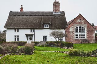 Exterior winter view of converted Victorian village school building adjoining 17th-century thatched cottage