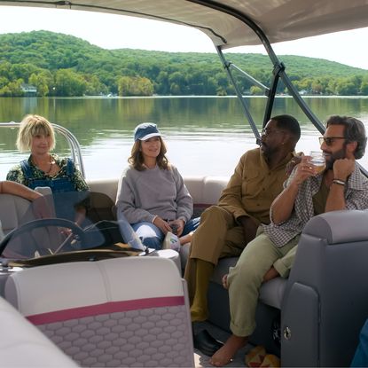 A group of people (l-r: Steve Carell as Nick, Kerri Kenney as Anne, Tina Fey as Kate, Colman Domingo as Danny, Marco Calvani as Claude, and Will Forte as Jack) sit on a boat in the middle of a lake, in Episode 101 of The Four Seasons.