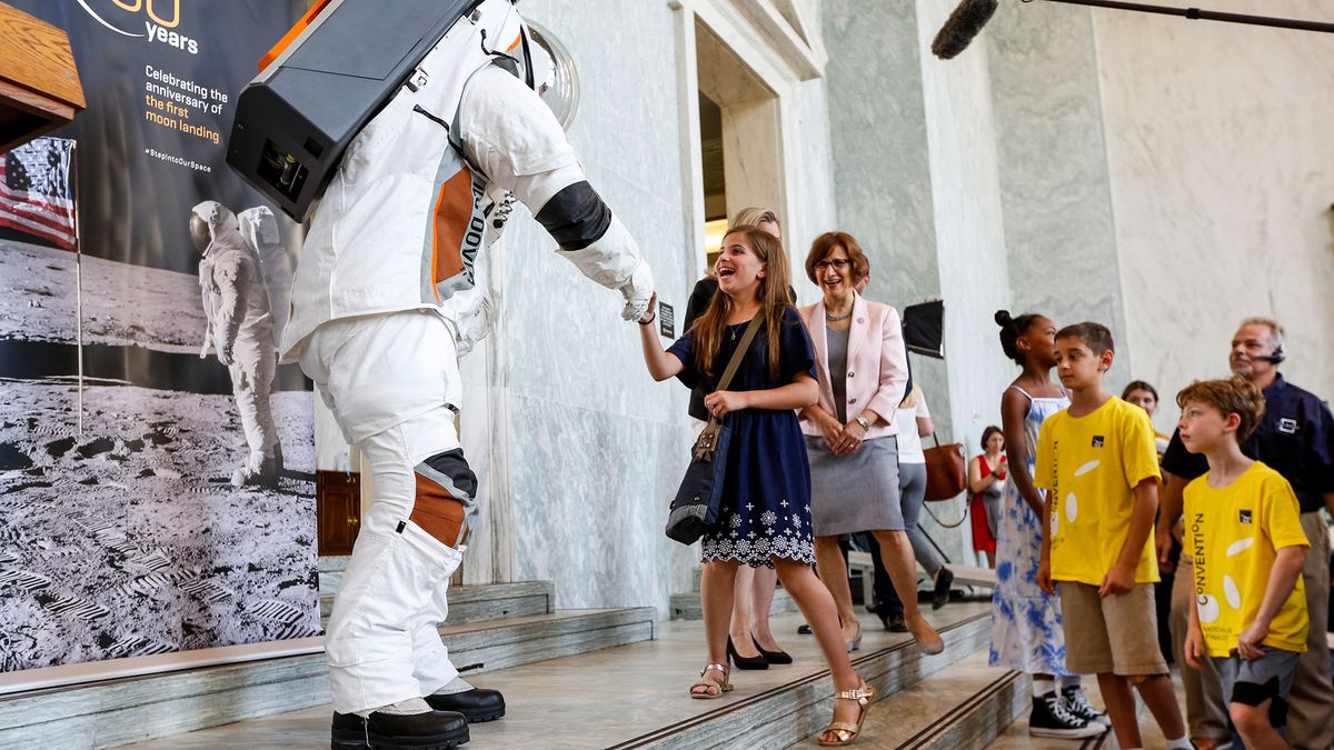 An engineer greets children while inside the prototype of Collins Aerospace, a unit of United Technologies Corp.'s Next Generation Space Suit system, unveiled during the Space Day on the Hill on Thursday, July 25, 2019 in Washington. The showcase was timed to commemorate the 50th Anniversary of Apollo 11.