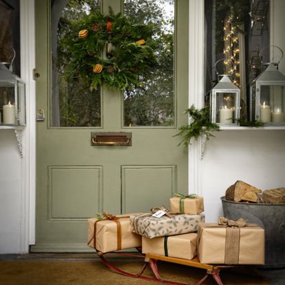 green front door with wreath and sled with Christmas presents