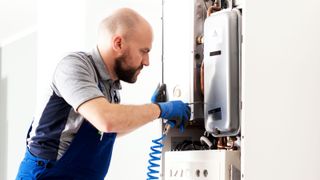 Man cleaning inside of a wall mounted boiler