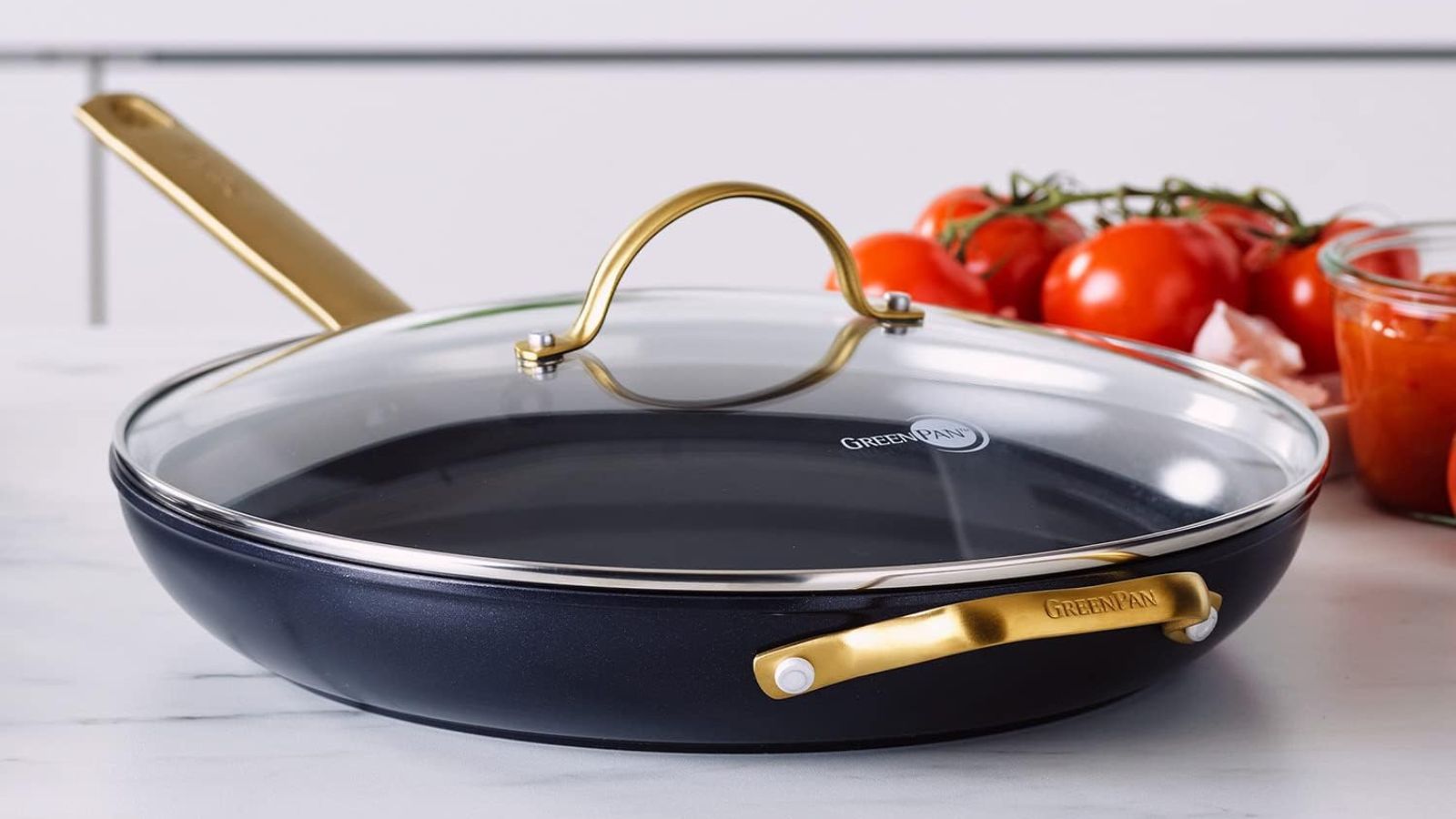 A GreenPan Ceramic Nonstick 12&quot; Frying Pan Skillet with Gold Handle and Lid on a modern counter next to fresh vine tomatoes