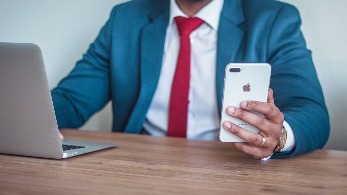 A picture of a man in a suit holding an iPhone