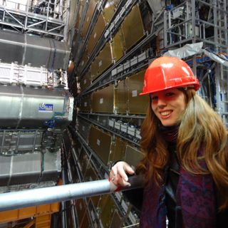Dr Clara Nellist (@ParticleClara on TikTok) standing next to the ATLAS detector at CERN.