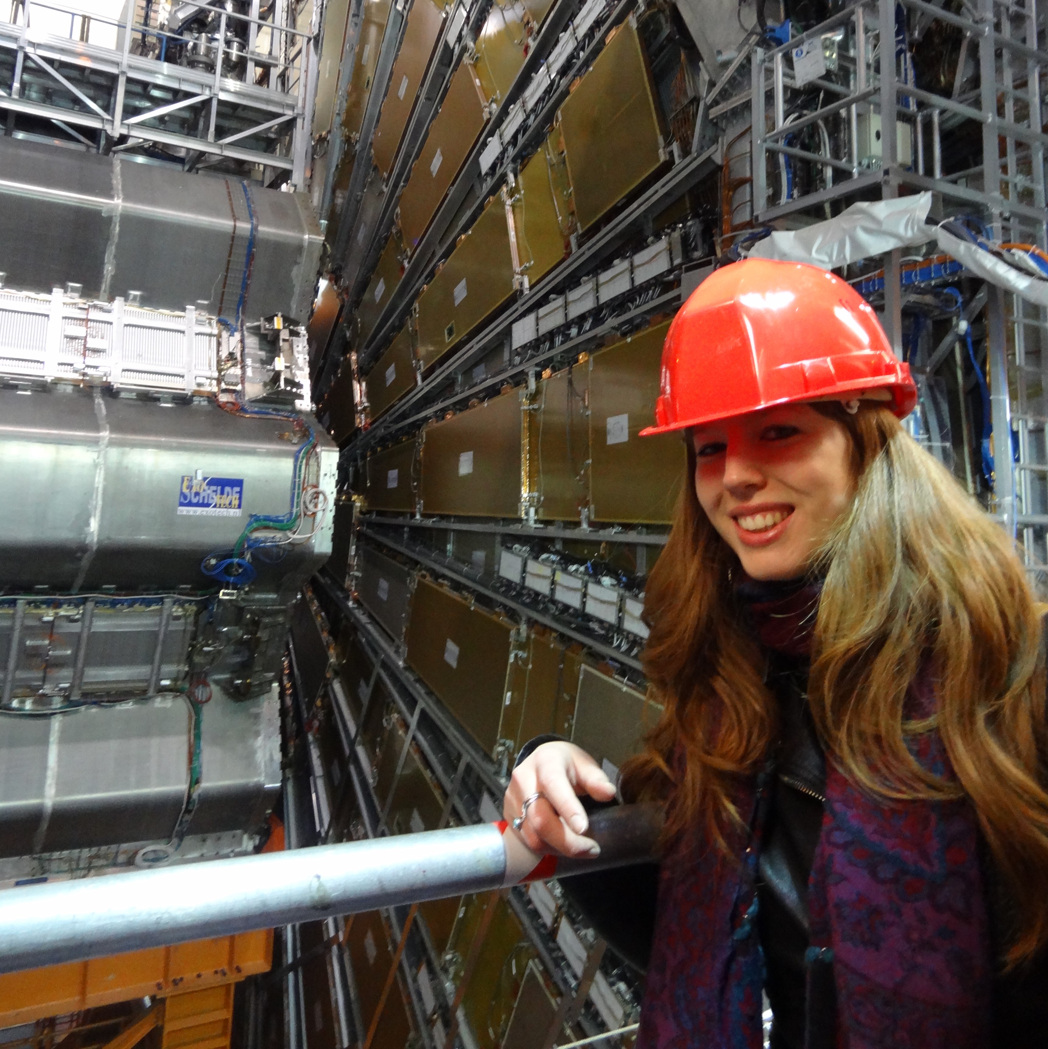Dr Clara Nellist (@ParticleClara on TikTok) standing next to the ATLAS detector at CERN.