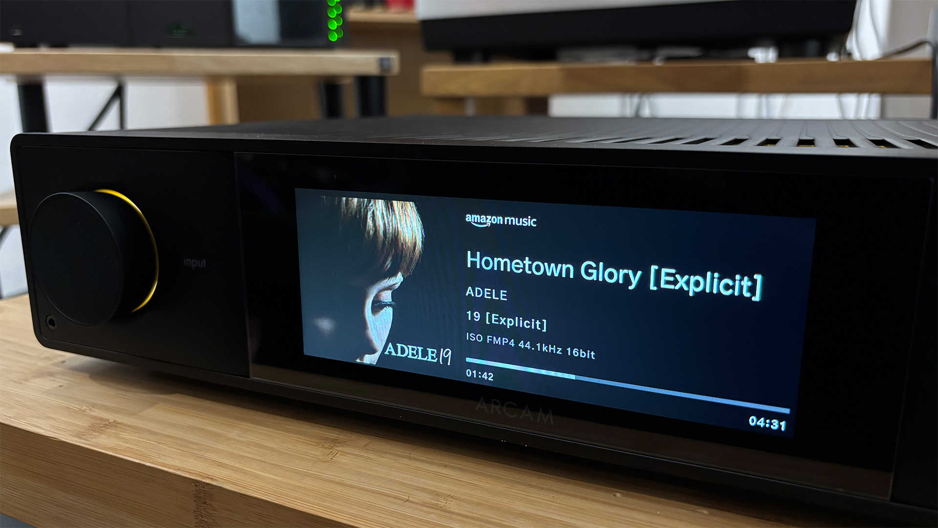 Arcam SA35 music streamer on wooden rack with song playing on display