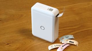 Niimbot D110 review; a small white box printer on a wooden table with colourful stickers