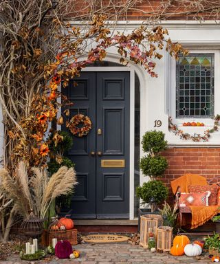 fall front door decorated with fall foliage and pumpkins with lanterns