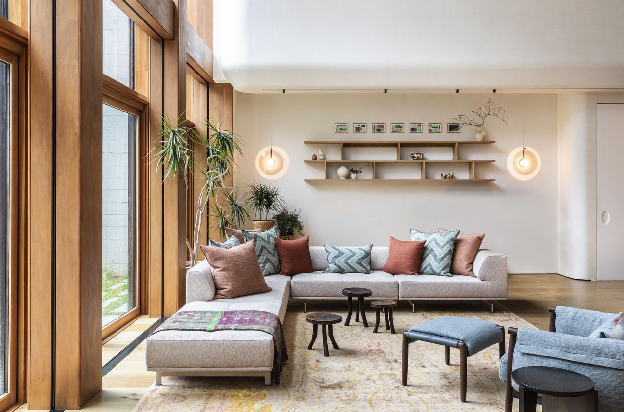 An L-shaped grey sofa nestles into the corner of a soaring living room space