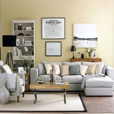 grey sofa against a pale yellow wall with a wooden coffee table and white bookcase