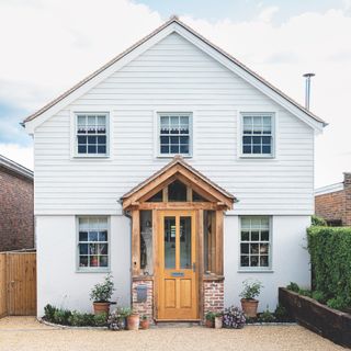 Front of house with wooden porch enclosure and white panelled cladding