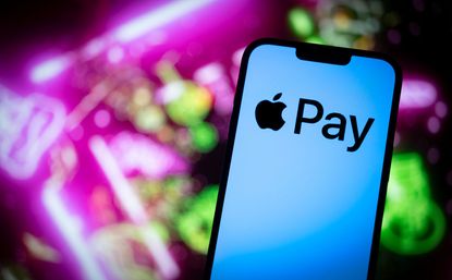 Apple Pay logo seen on smartphone with bright pink and green lights blurred in the background
