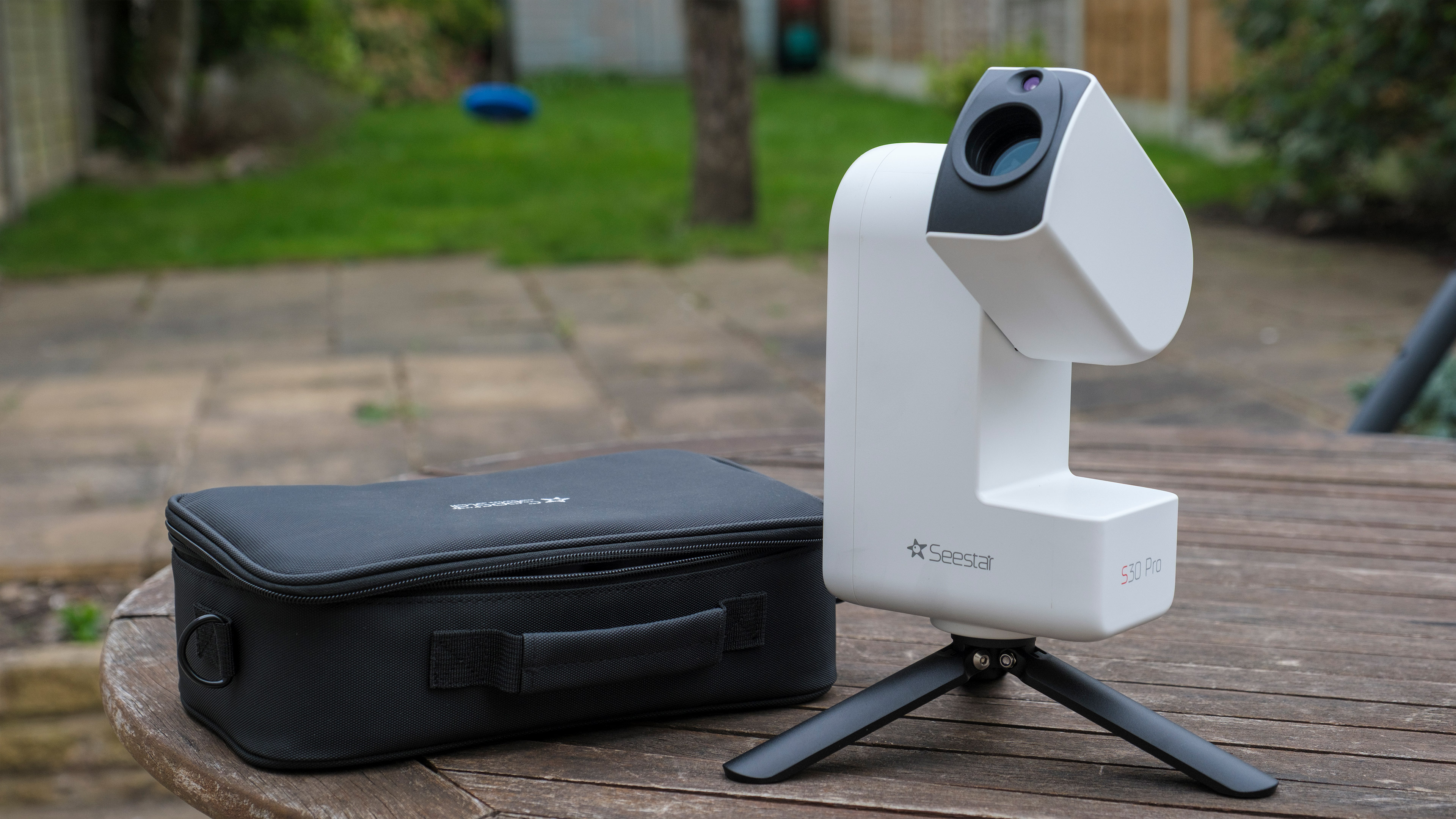 The ZWO Seestar S30 Pro on a table with arm open, next to its carrying case