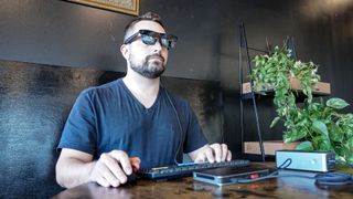 A person using Xreal One AR glasses with the Khadas Mind 2S mini PC at a coffee shop