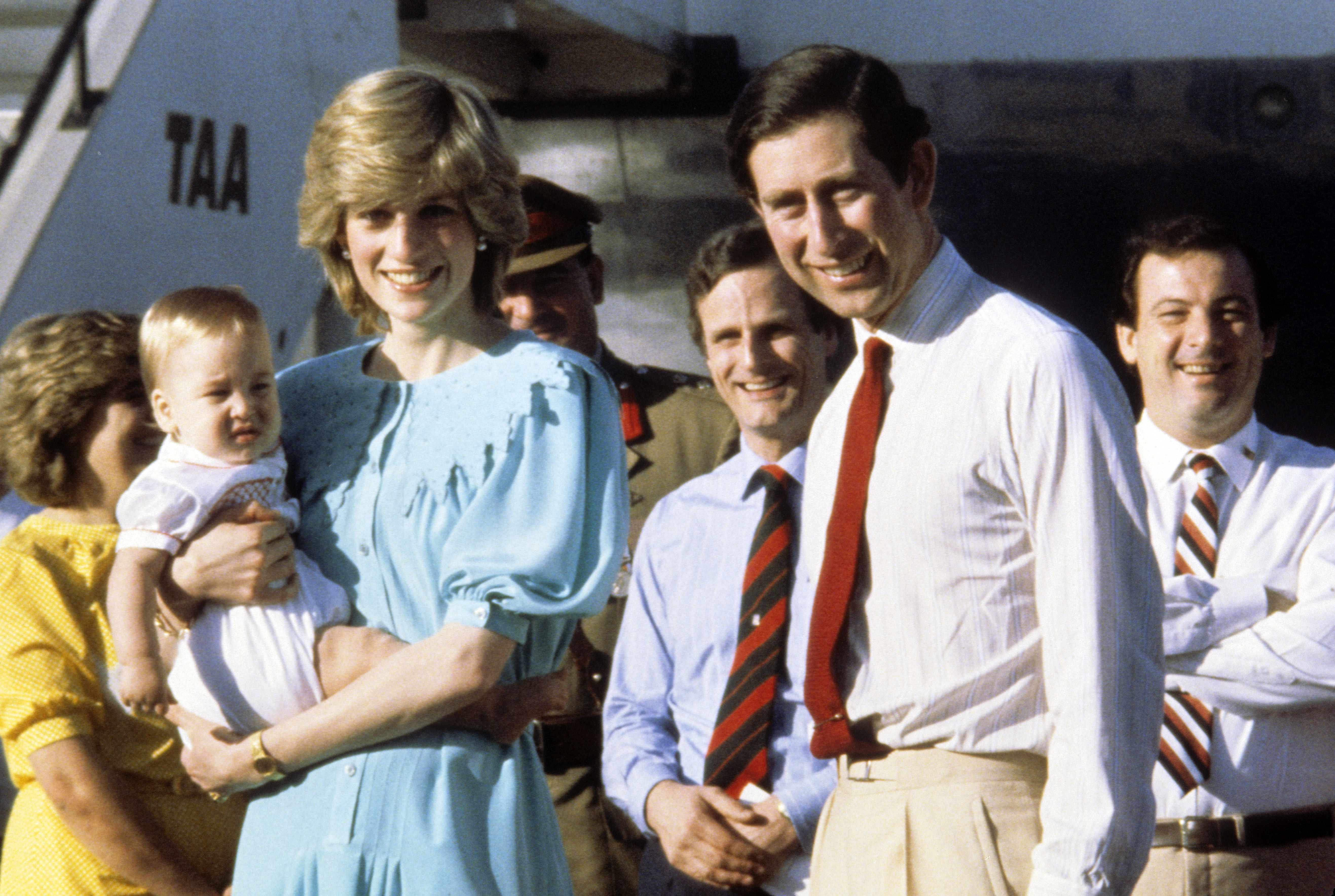 Princess Diana wears a Jan Van Velden dress and holds baby Prince William, while standing alongside King Charles, as they arrive at Alice Springs Airport at the start of their tour of Australia on March 20, 1983