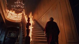 A shadowy figure ascends a staircase that's on fire