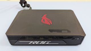 Asus ROG NUC 970sitting flat on a desk, plugged in with the logo glowing