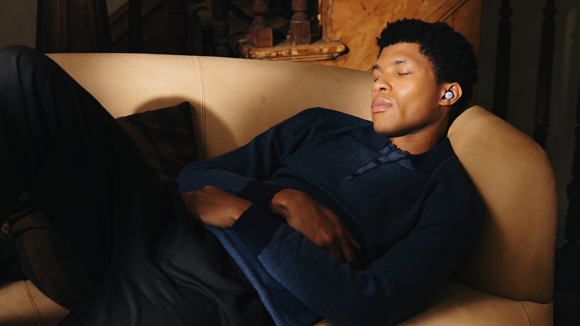 A man wearing a pair of NextSense Smartbuds takes a nap on the couch