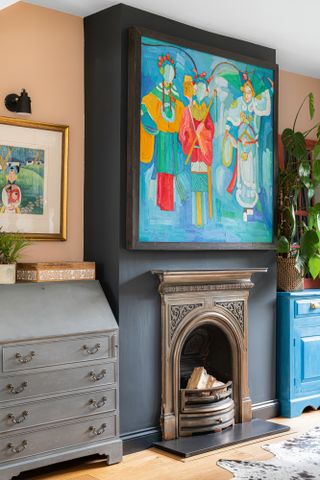 Living room with black painted fireplace, statement wall art and peach alcove paint