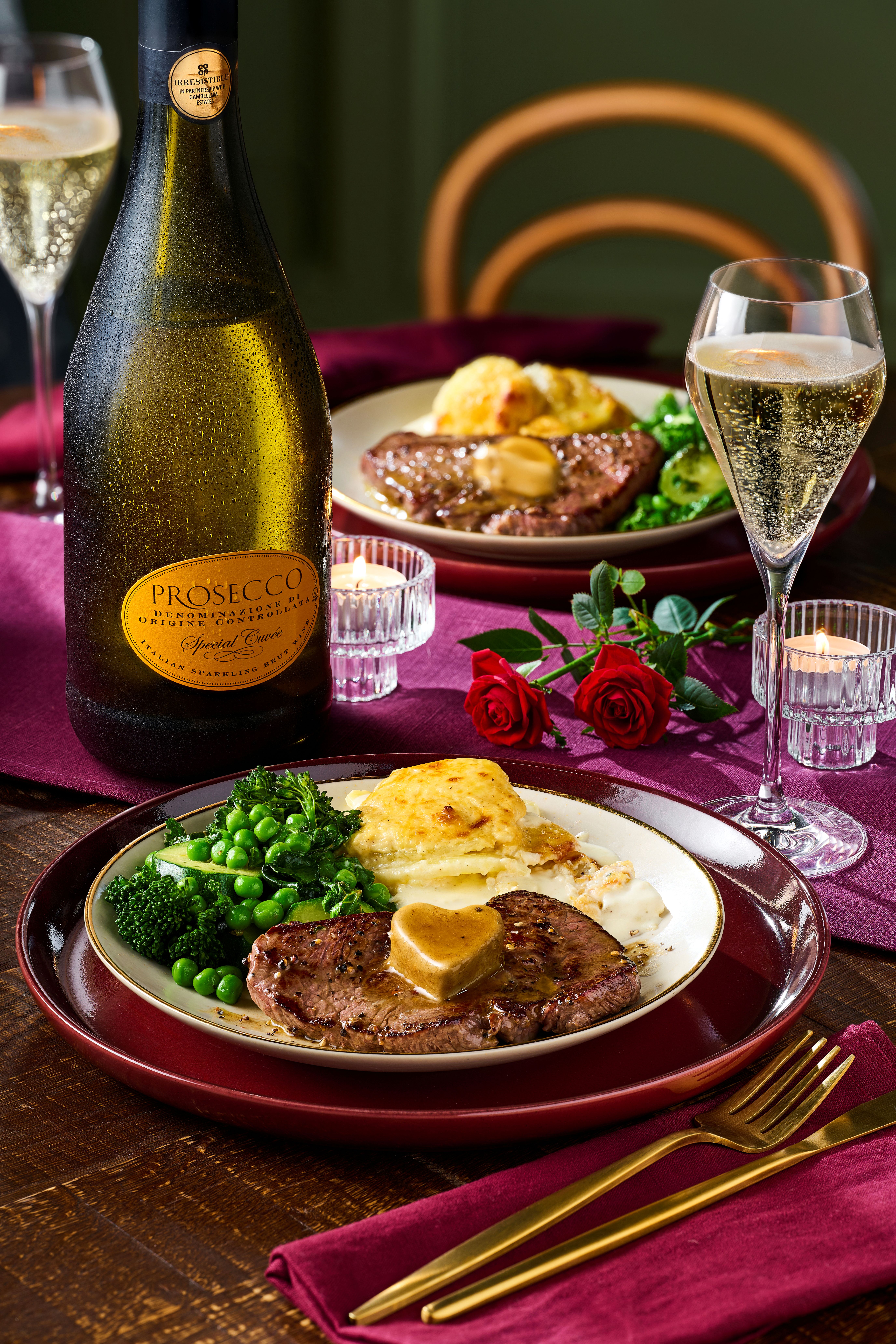 A bottle of Prosecco and a steak dinner on a romantic table for Valentine's Day