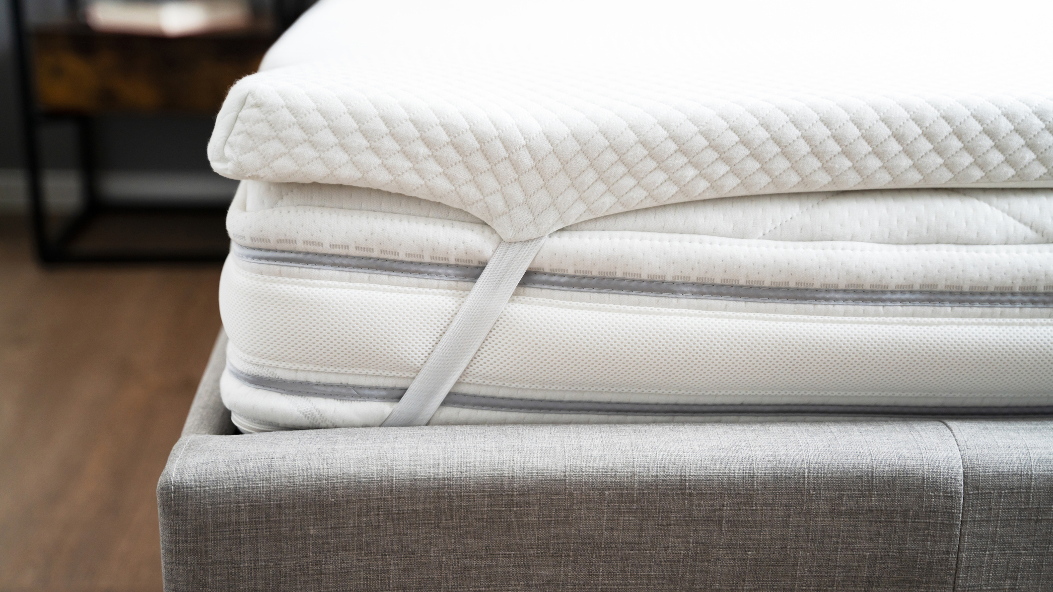 Gambar menunjukkan kasur busa memori di dasar tempat tidur kain abu-abu dan dengan penutup