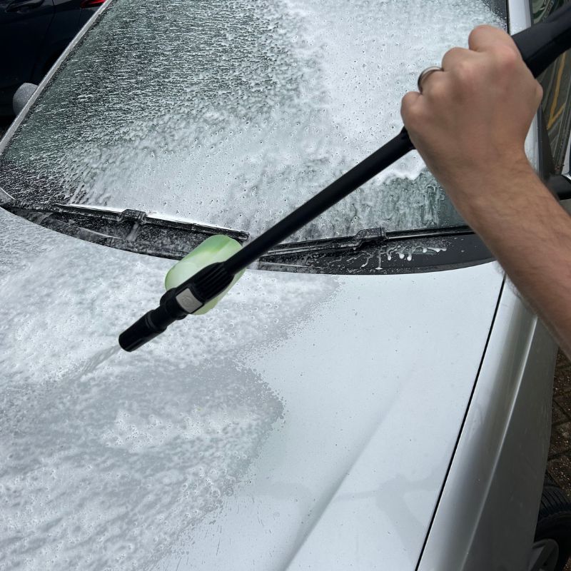 Webb pressure washer with dispenser attachment spraying detergent on silver car