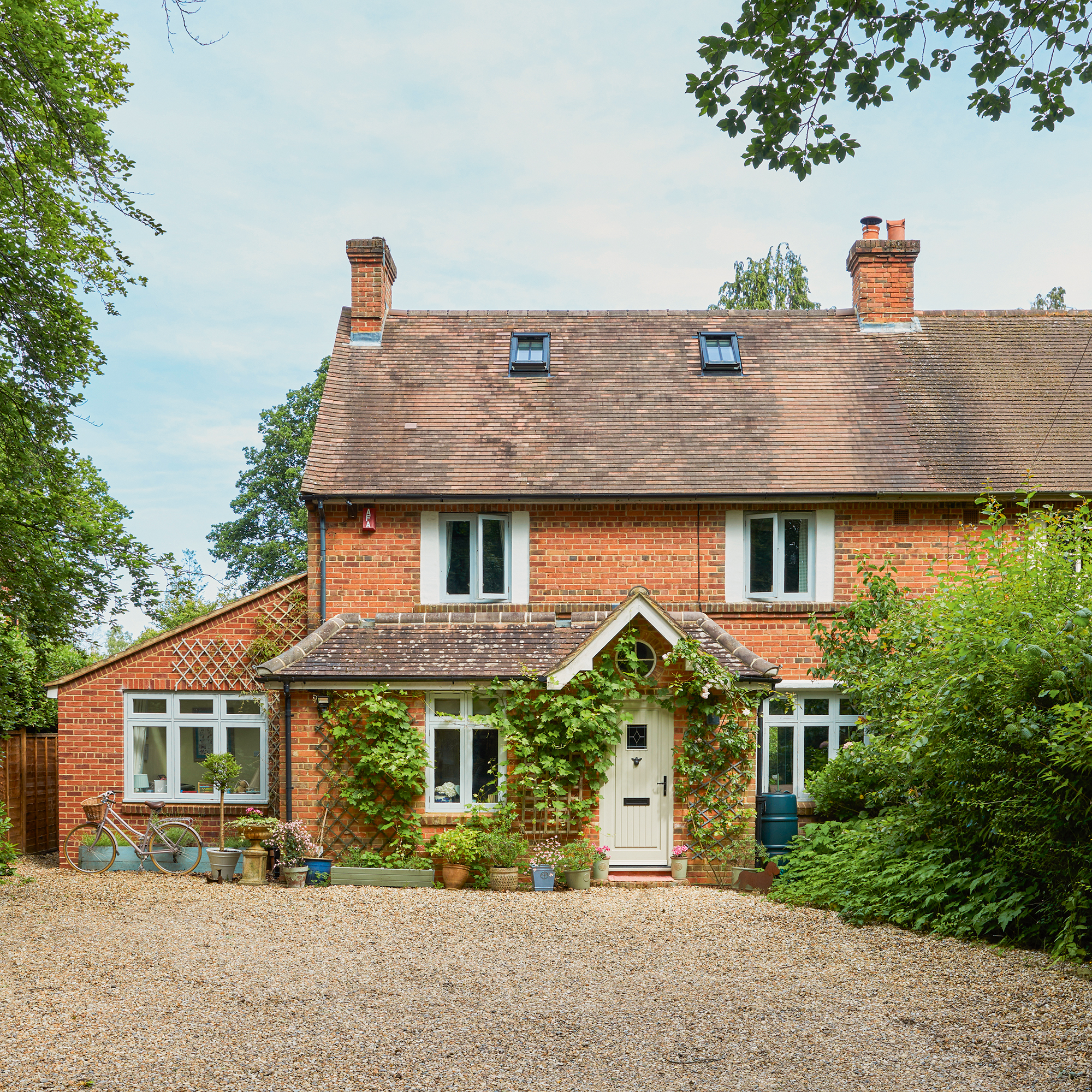 exterior of a country cottage with porch covered in climbing roses and a side extension