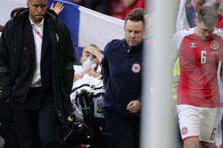 Paramedics using a stretcher to take Denmark’s Christian Eriksen off the pitch after he collapsed
