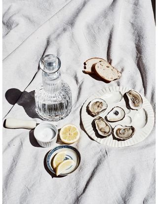 White oyster plate set on sheet with water decanter and accompaniments