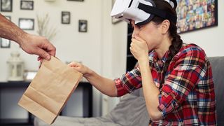 VR headset wearer being passed a sick bag