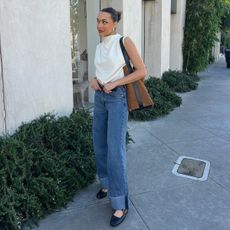 anneliese henderson wearing jeans and a white top and a suede bag