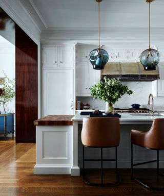 kitchen with brown bar stools and white units with dark wood floor