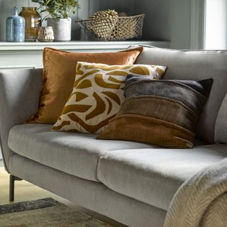 grey sofa with patterned cushions and grey throw