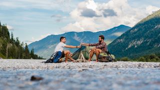 two men camping near a river