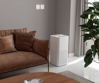 An air purifier by a brown sofa and a coffee table in a lounge
